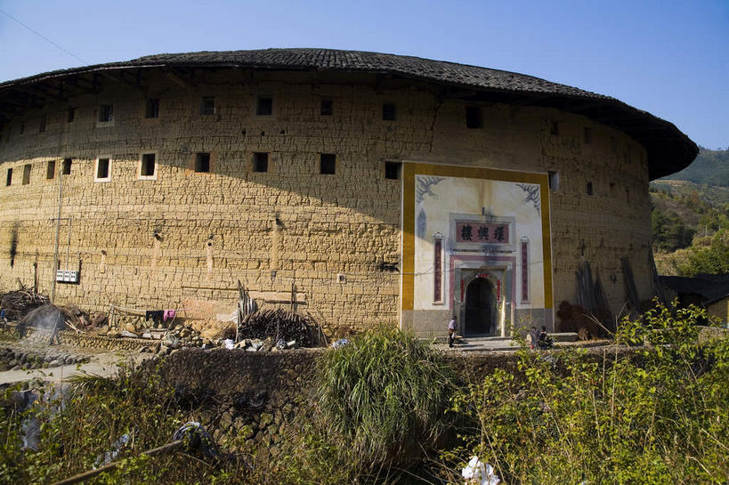 无人,家,横图,室外,白天,仰视,旅游,度假,名胜古迹,山,山脉,植物,门,标志建筑,地标,建筑,中国,亚洲,阴影,遗迹,光线,瓦片,影子,房屋,墙,屋顶,屋檐,屋子,山峰,山峦,顶棚,古迹,文物,娱乐,建设,古建筑,楼房,檐,墙壁,墙面,住宅,树,树木,蓝色,绿色,蓝天,天空,阳光,自然,门框,群山,天,享受,休闲,旅游胜地,放松,生长,晴朗,成长,福建,古文明,东亚,土楼,福建省,永定县,万里无云,中华人民共和国,华东地区,闽,龙岩,龙岩市,晴空,晴空万里,彩图,低角度拍摄,房子,福建土楼,客家土楼,客家土围楼,圆形围屋,永定土楼