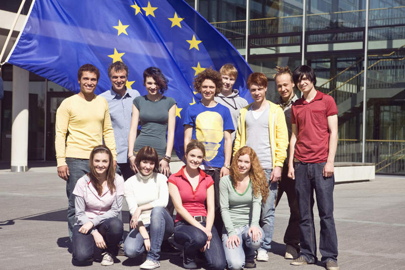 西方人,伙伴,朋友,教师,站,蹲,笑,微笑,露齿笑,横图,室外,白天,正面,友谊,旗帜,欧洲,欧洲人,一面,一排,阴影,服装,整齐,并列,并排,环绕,飘扬,围绕,光线,影子,星星,许多人,环抱,注视,休闲装,排列,衣服,黄色,蓝色,阳光,观察,看,站着,一群人,休闲,星形,同学,休闲服,服饰,观看,飘逸,察看,校友,队列,关注,飞扬,平行,五角形,欧盟旗帜,同窗,学友,萦绕,友情,男人,男性,年轻男性,年轻女性,女人,女性,中年男性,白种人,讲师,教授,老师,旗,五角星,蹲着,站立,彩图,全身