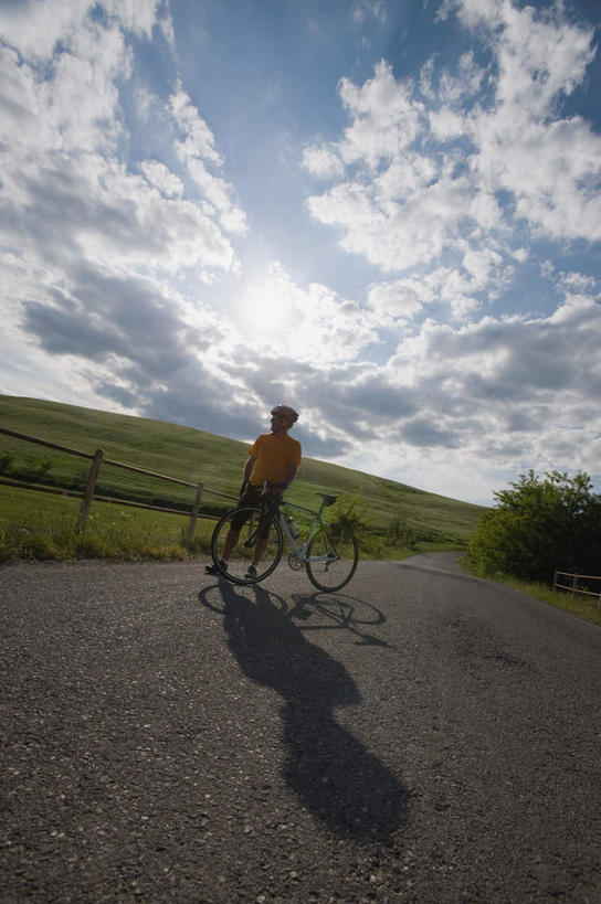 一个人,栏杆,站,竖图,室外,白天,正面,运动服,锻炼,旅游,度假,运动,太阳,道路,路,公路,自行车,帽子,仅一个男性,仅一个人,弯腰,阴影,服装,光线,头盔,影子,栅栏,旷野,篱笆,田野,云,云朵,围栏,交通,云彩,娱乐,踩,护栏,车,脚踏车,仅一个年轻男性,衣服,蓝色,白云,蓝天,天空,阳光,安全帽,交通工具,天,踩着,驾驶,行驶,站着,享受,休闲,放松,服饰,操纵,控制,载具,原野,室外运动,户外运动,操控,弯身,把持,男人,男性,年轻男性,马路,站立,彩图,全身,健身,运动装