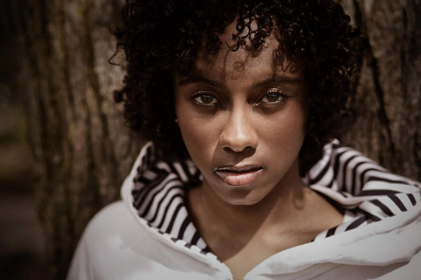 西方人,脸,头,脸颊,一个人,站,横图,室外,特写,白天,正面,植物,欧洲,非洲,黑人,欧洲人,仅一个年轻女性,仅一个女性,仅一个人,阴影,服装,光线,影子,注视,休闲装,肩膀,树,树木,衣服,绿色,白色,阳光,自然,靠,靠着,倚靠,站着,休闲,休闲服,凝视,服饰,生长,成长,倚着,凝望,谛视,年轻女性,女人,女性,非洲人,头部,卷发,脸部,脸蛋,面部,站立,半身,彩图