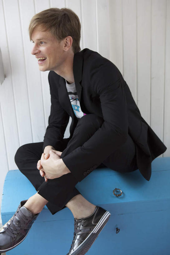 西方人,一个人,坐,笑,微笑,露齿笑,竖图,室内,白天,正面,椅子,欧洲人,仅一个男性,仅一个人,仅一个中年男性,握,服装,墙,注视,休闲装,墙壁,墙面,衣服,蓝色,黑色,观察,看,休闲,休闲服,搭,握着,服饰,观看,察看,搭着,关注,男人,男性,中年男性,白种人,坐着,彩图,全身