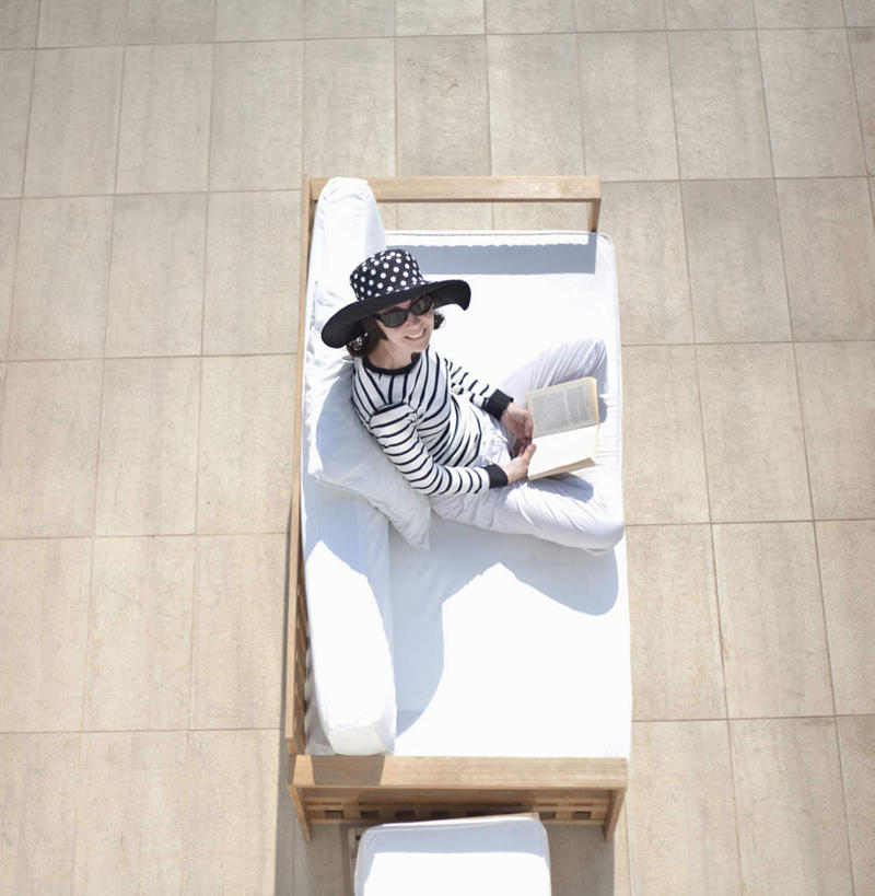 西方人,一个人,坐,笑,盘腿,微笑,露齿笑,竖图,俯视,室外,白天,地板,靠垫,帽子,书籍,椅子,欧洲,欧洲人,仅一个女性,仅一个人,一本,阴影,条纹,服装,光线,影子,木椅,靠枕,地面,注视,休闲装,木地板,衣服,白色,阳光,遮阳帽,垫子,枕头,打开,看,仅一个中年女性,休闲,休闲服,服饰,开启,关注,女人,女性,中年女性,白种人,书,图书,盘腿而坐,盘膝,盘着腿的,盘着腿坐,双腿交叉,抬头,仰头,坐着,彩图,高角度拍摄,全身