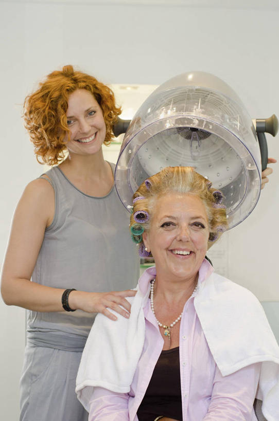 西方人,两个人,理发师,站,坐,笑,微笑,露齿笑,竖图,室内,白天,正面,欧洲,欧洲人,纺织物,工具,墙,扭头,注视,设备,顾客,墙壁,墙面,装饰品,饰品,手链,首饰,毛巾,扶,观察,看,清洁,站着,转头,搭,手镯,观看,保暖,卷发棒,卷发器,察看,扶着,搭着,关注,镯子,烫发机,烫发器,透气,防水,美发工具,主顾,储水,耐磨,吸水,塑料卷发棒,美发设备,年轻女性,女人,女性,中年女性,白种人,发型师,理发员,美发师,站立,坐着,半身,彩图