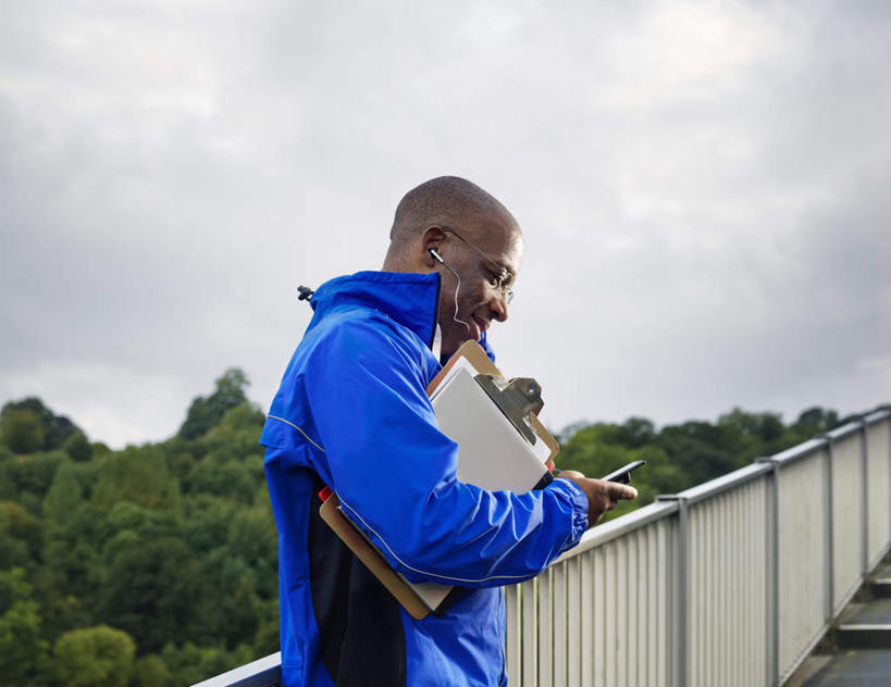 西方人,秃头,一个人,栏杆,站,笑,打电话,微笑,横图,室外,白天,侧面,树林,植物,道路,路,公路,电话,手机,欧洲,非洲,黑人,欧洲人,仅一个男性,仅一个人,仅一个中年男性,握,服装,乌云,云,阴天,云朵,围栏,交通,拿,云彩,拿着,注视,休闲装,通讯设备,护栏,树,树木,衣服,蓝色,绿色,天空,自然,天,观察,看,站着,休闲,休闲服,握着,服饰,生长,成长,观看,察看,昏暗,阴沉,关注,记录板,记事板,交流,男人,男性,中年男性,非洲人,光头,无发,马路,沟通,通话,站立,半身,彩图