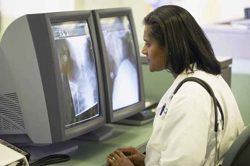 一个人,医生,办公室,坐,笑,微笑,露齿笑,横图,x光片,室内,白天,侧面,职员,电脑,桌子,非洲,黑人,双手,仅一个人,朦胧,模糊,辐射,科学,医学,注视,显示屏,听诊器,观察,看,台式电脑,观看,两台,察看,医疗,放置,科学技术,x射线,关注,x光,女人,女性,非洲人,医师,坐着,半身,彩图,电磁波,电磁辐射
