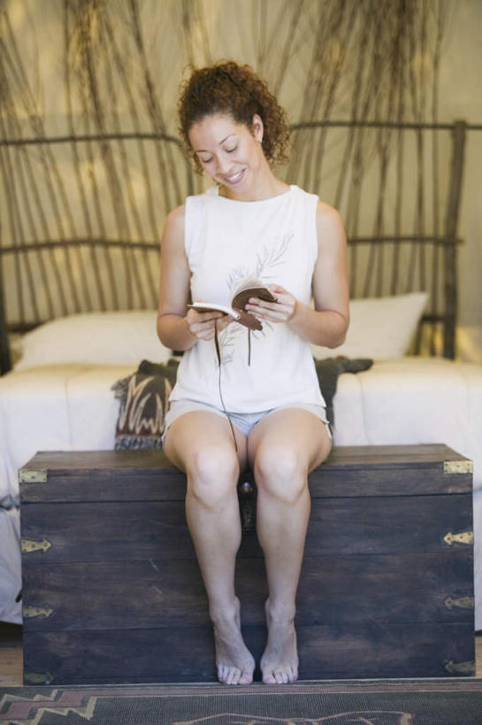 腿部,脚,脚趾,脚趾甲,腿,一个人,坐,笑,微笑,露齿笑,竖图,室内,白天,正面,度假,床,非洲,仅一个人,短裤,服装,木制,背心,帐篷,床单,拿,拿着,注视,休闲装,光脚,娱乐,上衣,束发,衣服,白色,笔记本,书本,箱子,枕头,低头,观察,看,休闲,休闲服,服饰,观看,踮脚,察看,关注,年轻女性,女人,女性,非洲人,脚指甲,卷发,坐着,彩图,全身