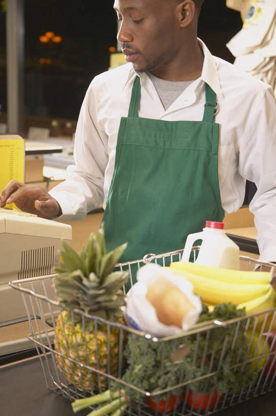 一个人,店员,商店,站,竖图,室内,白天,正面,衬衫,购物,消费,植物,苹果,菠萝,香蕉,蔬菜,西红柿,水果,非洲,黑人,仅一个男性,仅一个人,服装,商品,围裙,注视,休闲装,仅一个年轻男性,衣服,绿色,自然,观察,看,站着,营业员,休闲,休闲服,服饰,生长,成长,观看,察看,关注,结账,收银机,销售人员,男人,男性,年轻男性,非洲人,售货员,番茄,半身,彩图,衬衣