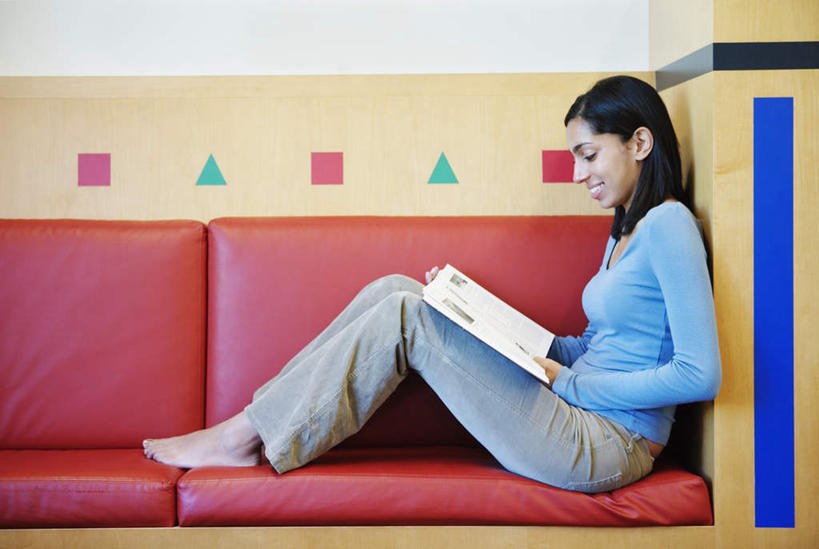 西方人,一个人,坐,捧,笑,微笑,露齿笑,横图,室内,白天,侧面,看书,阅读,地板,沙发,书架,书籍,椅子,欧洲,欧洲人,仅一个年轻女性,仅一个女性,仅一个人,服装,裤子,装饰,墙,地面,靠背椅,拿,拿着,牛仔裤,休闲装,顶灯,墙壁,灯,画,衣服,灯具,靠,靠着,休闲,休闲服,读书,浏览,服饰,照明工具,年轻女性,女人,女性,白种人,装饰画,端,端着,捧着,坐着,彩图,全身,皮沙发