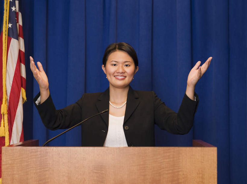 东方人,一个人,商务人士,商务女性,站,举,笑,微笑,露齿笑,横图,室内,白天,正面,旗帜,国旗,项链,亚洲,仅一个年轻女性,仅一个女性,仅一个人,一条,阴影,套装,反射,影子,注视,黄种人,星条旗,装饰品,讲台,饰品,首饰,观察,看,托,站着,美国国旗,观看,察看,关注,演说台,商务装,工薪阶层,演讲台,年轻女性,女人,女性,亚洲人,白领,上班族,旗,举起,举手,举着,向上举,向上伸,向上托,站立,半身,彩图,美利坚合众国国旗