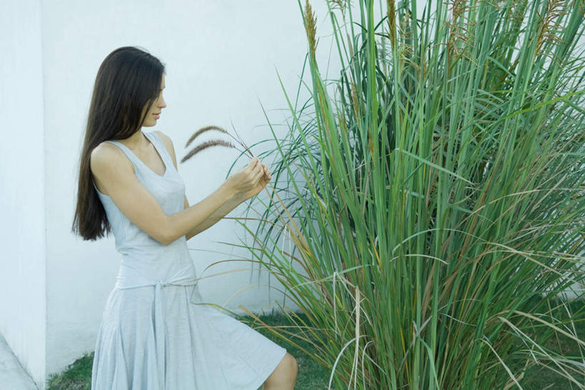 西方人,一个人,站,笑,微笑,露齿笑,横图,室外,白天,侧面,草地,草坪,植物,芦苇,叶子,欧洲,欧洲人,仅一个年轻女性,仅一个女性,仅一个人,服装,墙,粽叶,绿叶,拿,拿着,注视,休闲装,狗尾巴草,墙壁,墙面,草,衣服,绿色,低头,观察,看,站着,休闲,休闲服,抓,嫩叶,服饰,观看,察看,关注,箬叶,芦苇叶,年轻女性,女人,女性,白种人,叶,叶片,站立,半身,彩图