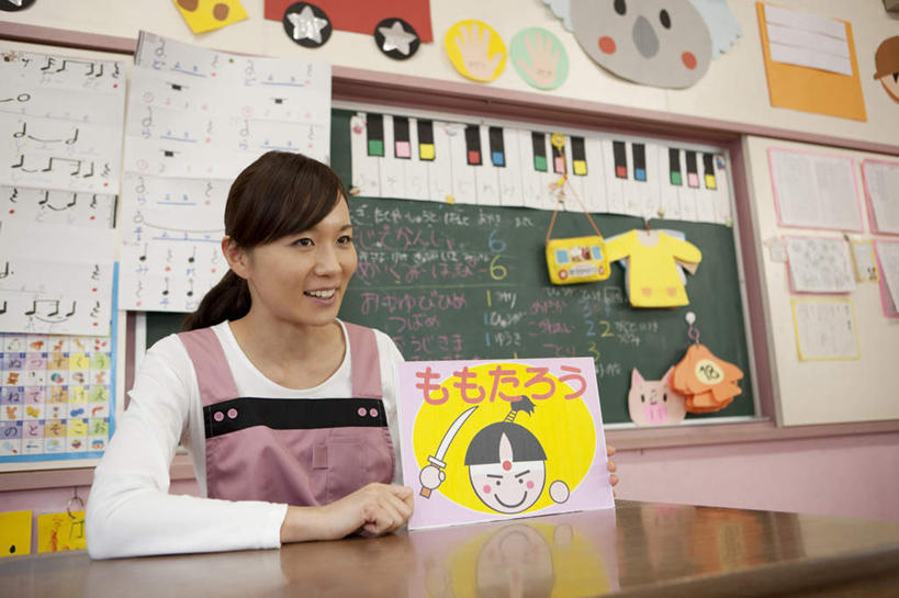 东方人,一个人,教师,坐,笑,微笑,露齿笑,横图,室内,白天,正面,桌子,书籍,亚洲,仅一个年轻女性,仅一个女性,仅一个人,拿,拿着,黄种人,书桌,课桌,黑板,教室,日本人,年轻女性,女人,女性,亚洲人,老师,书,图书,坐着,半身,彩图