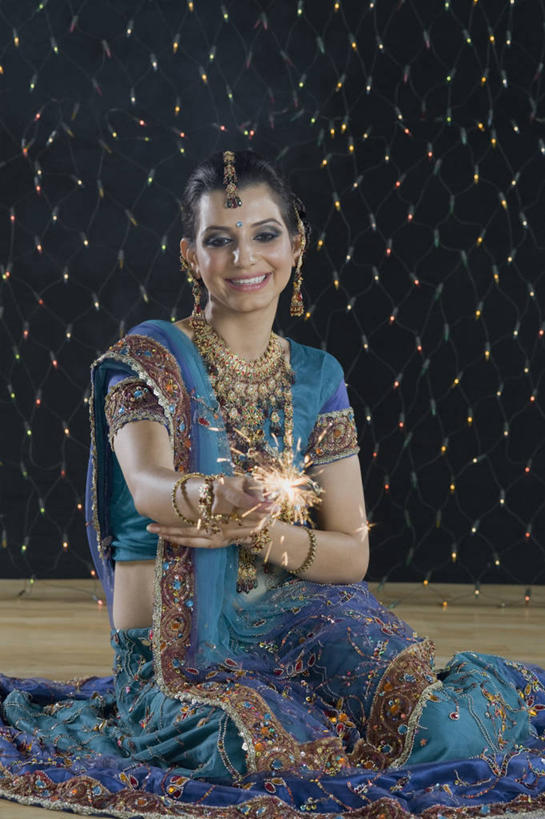 一个人,坐,笑,微笑,露齿笑,竖图,室内,白天,正面,民族服装,烟火,项链,亚洲,仅一个年轻女性,仅一个女性,仅一个人,握,阴影,光线,影子,灯光,注视,一个,焰火,耳环,手链,观察,看,握着,服饰,手镯,单个,观看,飘逸,察看,庄重,关注,礼花,追求,镯子,仙女棒,纱丽,雅致,花炮,礼花炮,耳饰,纱丽服,清婉,妍丽,手持喷泉,手持烟花,年轻女性,女人,女性,亚洲人,印度人,烟花,坐着,半身,彩图,传统服装,民俗服,奢华