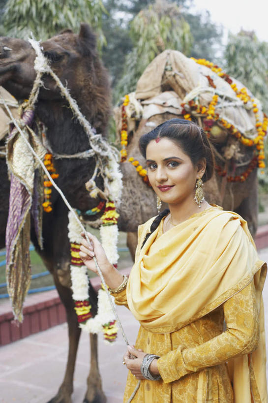 一个人,站,笑,微笑,竖图,室外,白天,正面,民族服装,旅游,度假,树林,植物,道路,路,公路,野生动物,亚洲,仅一个年轻女性,仅一个女性,仅一个人,握,朦胧,模糊,装饰,交通,拿,拿着,注视,娱乐,骆驼,树,树木,绿色,自然,动物,绳子,观察,看,站着,享受,休闲,放松,可爱,握着,服饰,活泼,生长,成长,观看,牵着,飘逸,察看,庄重,关注,追求,凶猛,纱丽,雅致,民族文化,纱丽服,清婉,妍丽,年轻女性,女人,女性,亚洲人,印度人,马路,玩耍,站立,半身,彩图,传统服装,民俗服,奢华