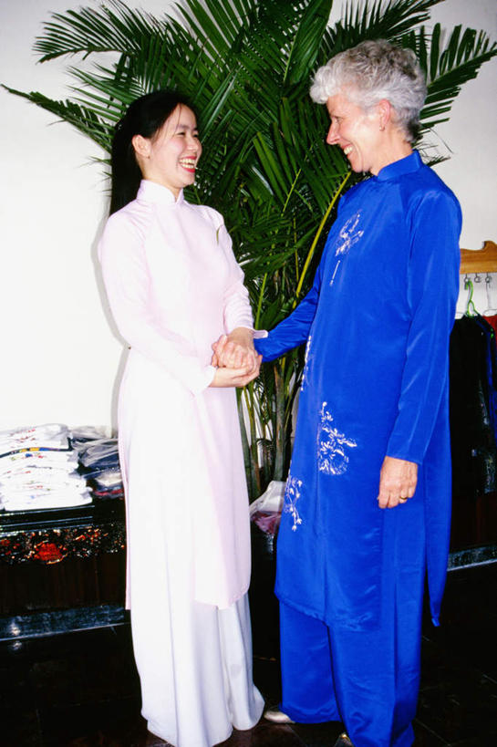 东方人,西方人,两个人,站,握手,笑,微笑,露齿笑,竖图,室内,白天,正面,民族服装,植物,欧洲,欧洲人,亚洲,盆栽,墙,盆景,注视,黄种人,墙壁,墙面,绿色,白色,自然,观察,看,站着,服饰,活泼,生长,成长,观看,察看,关注,老年女性,女人,女性,中年女性,白种人,亚洲人,搀手,拉手,手拉手,手握手,站立,彩图,全身,传统服装,民俗服,奥黛