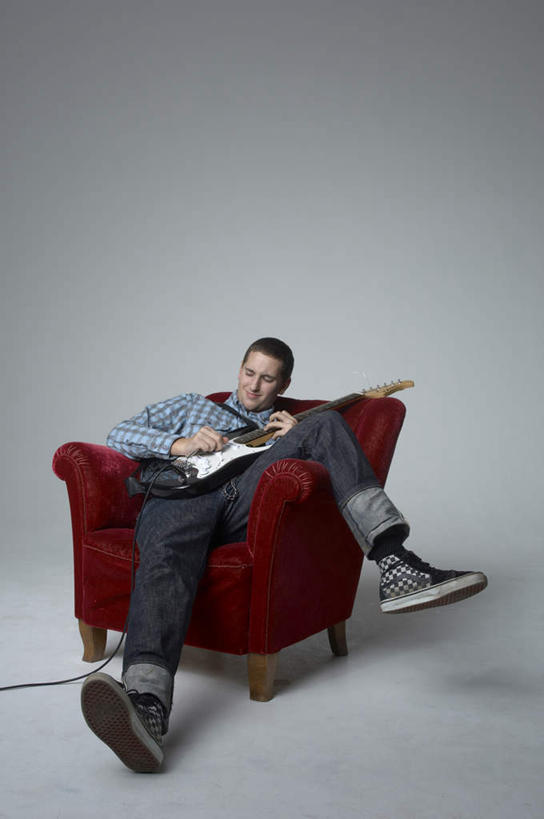 西方人,一个人,坐,举,笑,微笑,竖图,室内,白天,正面,沙发,欧洲,欧洲人,仅一个男性,仅一个人,握,灰色背景,服装,电吉他,乐器,弦乐器,拿,拿着,休闲装,仅一个年轻男性,衣服,红色,托,休闲,休闲服,弹琴,握着,摄影,服饰,影棚,弹拨弦鸣乐器,布艺沙发,奏琴,抚琴,男人,男性,年轻男性,白种人,举起,举手,举着,向上举,向上伸,向上托,坐着,彩图,全身,影棚拍摄,拍摄,弹拨弦乐器