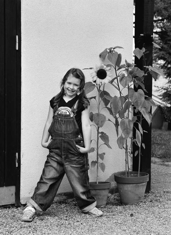 西方人,儿童,一个人,站,笑,微笑,露齿笑,竖图,黑白,室外,白天,正面,爱情,幸福,纯洁,太阳,植物,向日葵,欧洲,欧洲人,仅一个女性,仅一个人,服装,盛开,盆栽,盆景,花蕾,注视,休闲装,花,花瓣,花朵,鲜花,小孩,衣服,绿色,自然,花苞,花蕊,观察,看,站着,仅一个小孩,休闲,休闲服,可爱,童年,童趣,服饰,生长,成长,观看,察看,关注,光辉,童真,烂漫,无邪,沉默,忠诚,双手抄兜,双手放兜,勇敢,投缘,爱慕,高傲,天真,朝阳花,葵花,望日莲,向阳花,转日莲,女孩,女人,女性,白种人,孩子,插兜,两手抄兜,两手放兜,手插兜,手放口袋,站立,全身,女生,手抄兜