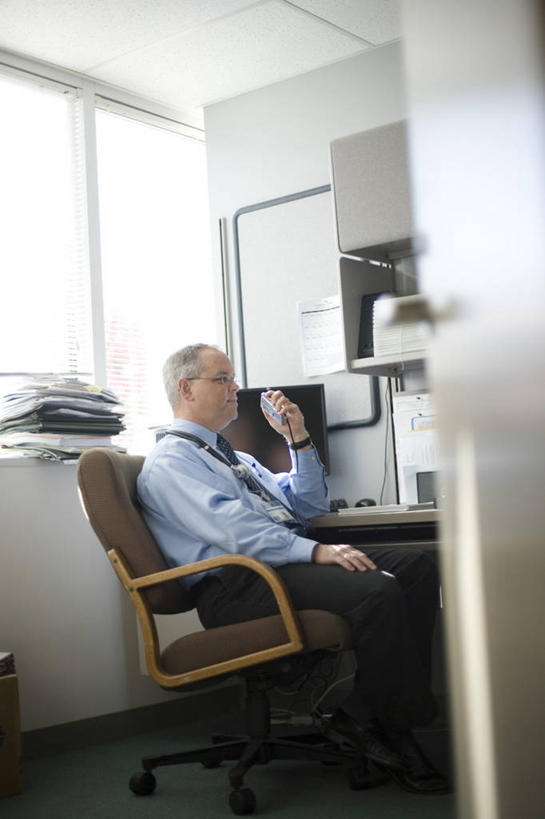 西方人,一个人,医生,医院,坐,竖图,室内,白天,侧面,衬衫,电脑,显示器,鼠标,键盘,窗户,窗帘,桌子,椅子,欧洲,欧洲人,仅一个男性,仅一个人,仅一个中年男性,一堆,许多,握,堆叠,堆积,装饰,网络,笔,材料,档案,文件,眼镜,纸,办公桌,墙,办公用品,领带,很多,拿,拿着,注视,输入设备,通讯设备,标识,吊牌,水笔,玻璃窗,墙壁,墙面,文具,帘子,会议椅,手稿,胸牌,学习用品,资料,观察,看,聆听,医护人员,医疗人员,遮阳,台式电脑,握着,观看,堆,录音机,华丽,修饰,办公椅,文具用品,证明,点缀,察看,徽章,关注,文档,通信设备,身份,近视眼镜,输出设备,胸章,医疗机构,胸卡,衬托,美观,雅致,雅观,商务椅,培训椅,编号牌,雕刻牌,工号牌,胸号牌,胸徽,员工牌,凝听,男人,男性,中年男性,白种人,大夫,坐着,半身,彩图,衬衣,病院,诊所