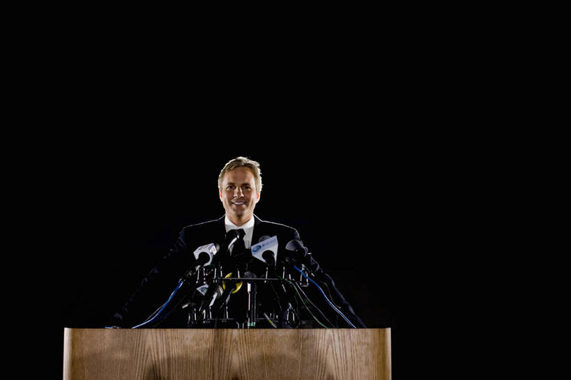 西方人,一个人,商务人士,商务男性,舞台,站,笑,微笑,露齿笑,横图,室内,白天,正面,衬衫,西装,欧洲,欧洲人,仅一个男性,仅一个人,仅一个中年男性,阴影,套装,正装,光线,影子,领带,注视,职业装,话筒,发言,观察,看,演讲,站着,观看,察看,麦克风,关注,扩音器,政治,传声器,工薪阶层,竞选,微音器,记者会,记者招待会,男人,男性,中年男性,白种人,白领,上班族,表演台,讲话,站立,半身,彩图,衬衣,演说家