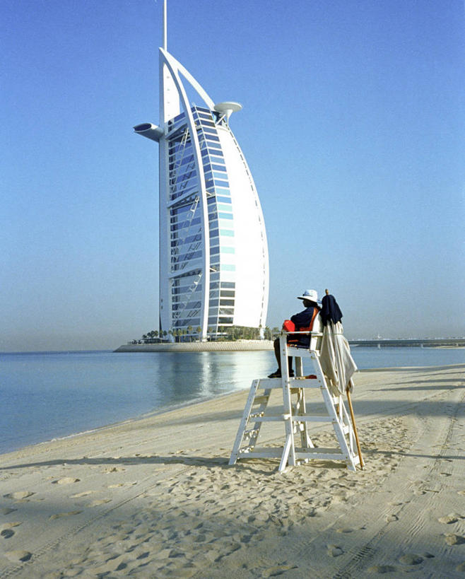 成年人,一个人,救生员,坐,竖图,室外,白天,安全,海洋,水,建筑,摩天大楼,帽子,仅一个男性,反射,沙子,地平线,水平线,天空,看,办公大楼,放松,摄影,观看,救生椅,环境,海景,阿拉伯联合酋长国,迪拜,万里无云,海滩,彩图,旅行,帆船酒店