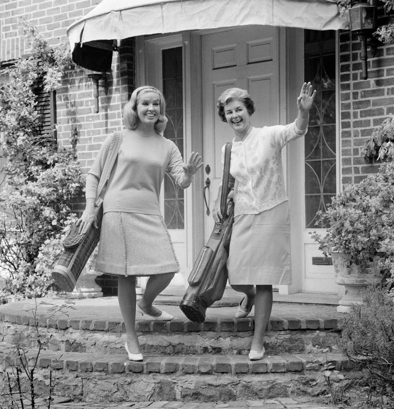 西方人,成年人,中年人,老年人,两个人,站,微笑,竖图,方图,黑白,室外,白天,快乐,建筑,欧洲,纽约,美国,欧洲人,房屋,庭院,古典,挥手,拿着,台阶,摄影,灌木,享乐,高尔夫球包,高尔夫球运动,老年女性,年轻女性,白种人,年轻人