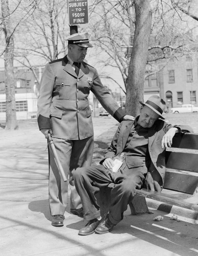 成年人,中年人,老年人,两个人,广场,站,坐,竖图,黑白,室外,白天,制服,帽子,美国,长椅,城镇,拿着,瓶子,酗酒,摄影,英文字母,警官,警棍,老年男性,男人,男性,触摸,睡觉,社会问题