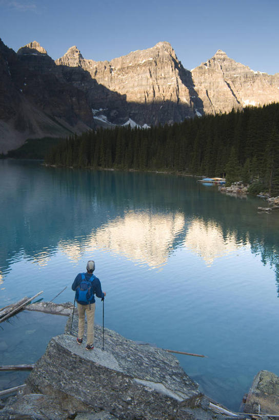 成年人,一个人,站,竖图,室外,白天,运动服,旅游,度假,日出,湖,美景,森林,山,山脉,水,日光,加拿大,仅一个男性,波纹,反射,景观,山顶,娱乐,背面,蓝色,自然,享受,休闲,表,景色,放松,摄影,岩层,自然风光,背包客,班夫国家公园,万里无云,登山杖,亚伯达,露易斯湖,冒险,岩石,彩图